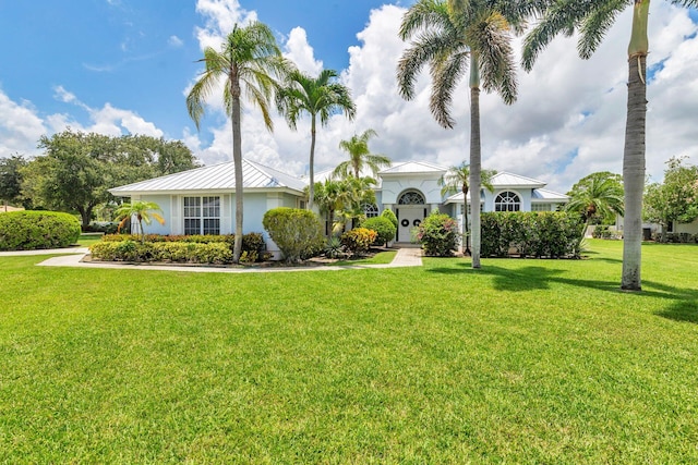 6025 Fountain Palm Dr, Jupiter, FL 33458 - view of front of house with a front yard, stucco siding, a metal roof, and a standing seam roof