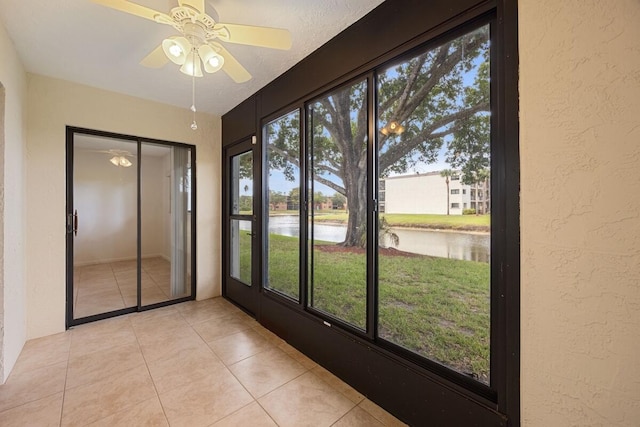 15378 Lakes Of Delray Blvd Unit 15, Delray Beach, FL 33484 - unfurnished sunroom with a textured wall, a water view, a ceiling fan, and tile patterned flooring
