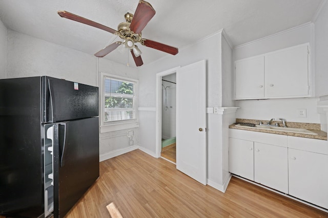 4621 N Ocean Blvd, Boynton Beach, FL 33435 - kitchen featuring freestanding refrigerator, light countertops, light wood-style flooring, white cabinetry, and ornamental molding