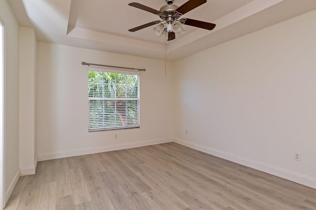 2113 SE Fern Park Dr, Port Saint Lucie, FL 34952 - empty room featuring a raised ceiling, light wood-style floors, and a ceiling fan