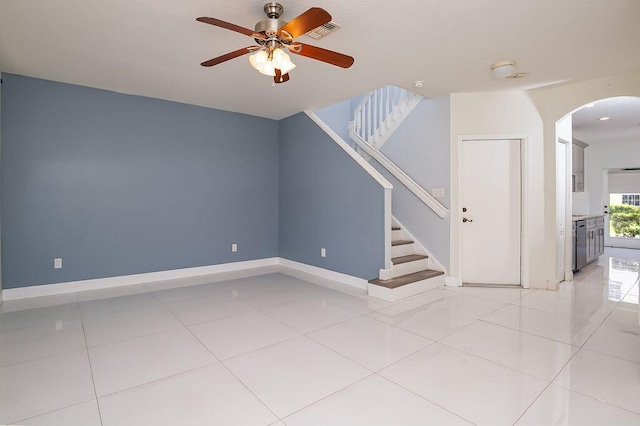 2113 SE Fern Park Dr, Port Saint Lucie, FL 34952 - unfurnished living room with arched walkways, ceiling fan, light tile patterned floors, and stairway