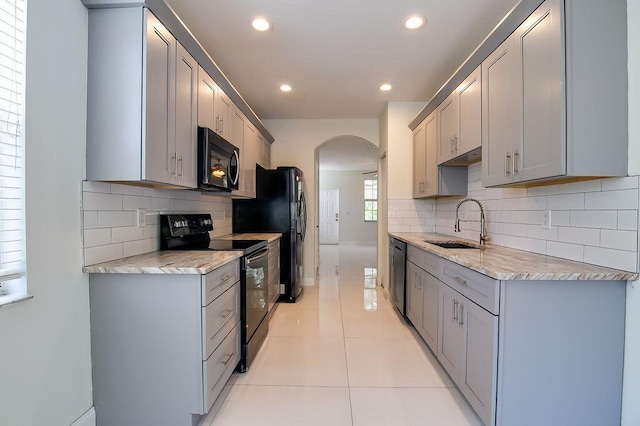 2113 SE Fern Park Dr, Port Saint Lucie, FL 34952 - kitchen with black appliances, gray cabinetry, arched walkways, recessed lighting, and backsplash