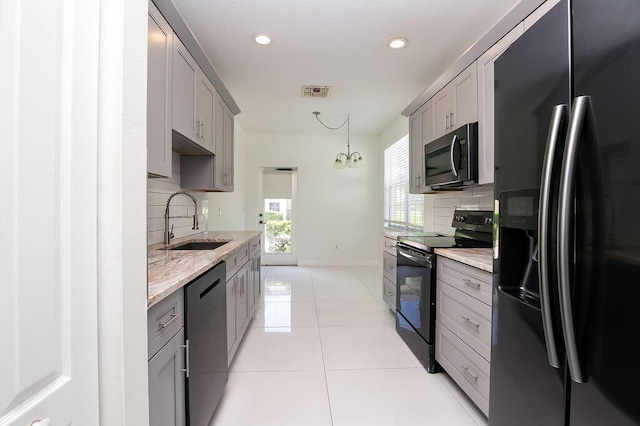 2113 SE Fern Park Dr, Port Saint Lucie, FL 34952 - kitchen featuring black appliances, gray cabinets, decorative backsplash, light tile patterned floors, and a chandelier