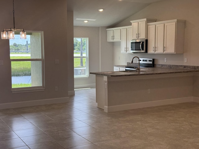 5117 Modeno St, Fort Pierce, FL 34951 - kitchen featuring stainless steel appliances, lofted ceiling, a peninsula, white cabinets, and a breakfast bar area