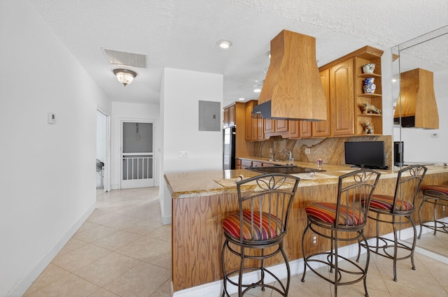 1111 Lemon Tree Ter Unit 204, Delray Beach, FL 33445 - kitchen with open shelves, a peninsula, light tile patterned flooring, backsplash, and brown cabinetry