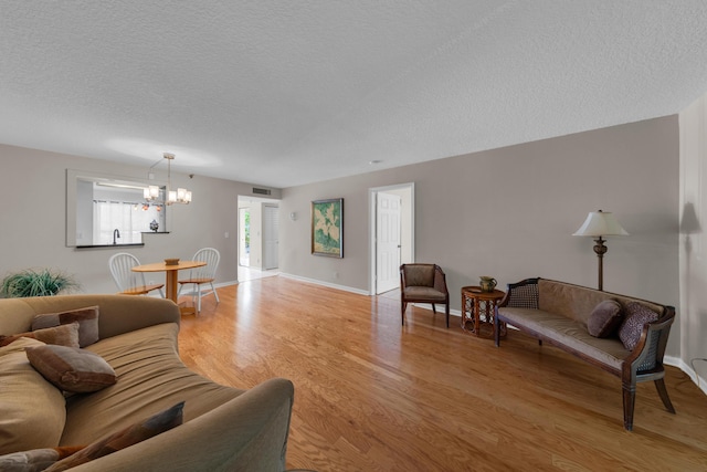 14623 Bonaire Blvd Unit 203, Delray Beach, FL 33446 - living room with a textured ceiling, light wood-style floors, and a chandelier