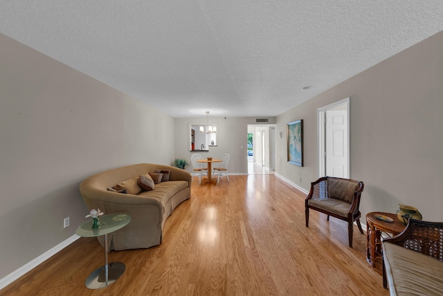 14623 Bonaire Blvd Unit 203, Delray Beach, FL 33446 - living room featuring light wood-style floors, a chandelier, and a textured ceiling