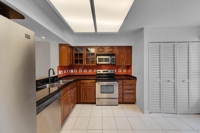 14623 Bonaire Blvd Unit 203, Delray Beach, FL 33446 - kitchen featuring stainless steel appliances, backsplash, glass insert cabinets, and brown cabinetry