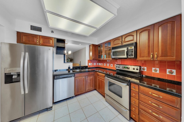 14623 Bonaire Blvd Unit 203, Delray Beach, FL 33446 - kitchen with appliances with stainless steel finishes, brown cabinets, glass insert cabinets, light tile patterned flooring, and backsplash