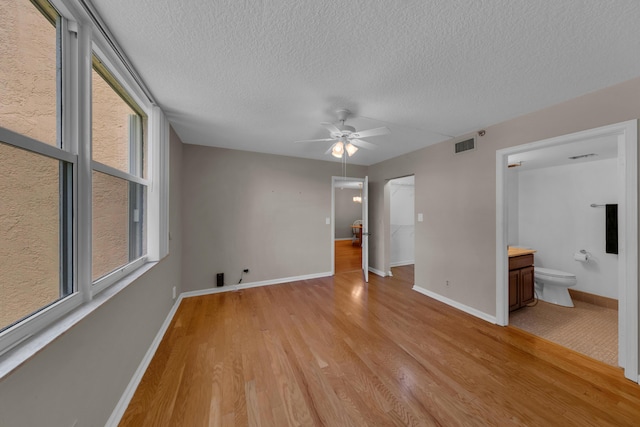 14623 Bonaire Blvd Unit 203, Delray Beach, FL 33446 - unfurnished bedroom with a textured ceiling, light wood-style flooring, connected bathroom, and ceiling fan