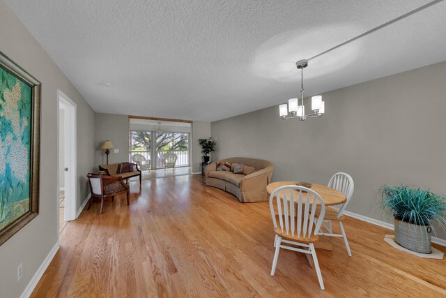 14623 Bonaire Blvd Unit 203, Delray Beach, FL 33446 - dining space featuring light wood finished floors, a textured ceiling, and a chandelier