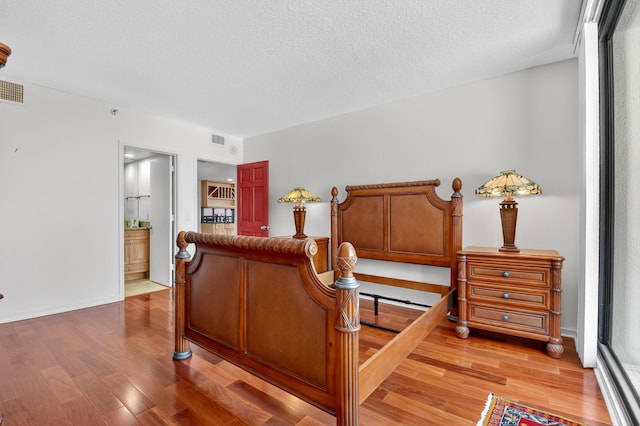 4000 N Ocean Dr Unit 204, Singer Island, FL 33404 - bedroom featuring light wood-type flooring, a textured ceiling, and connected bathroom