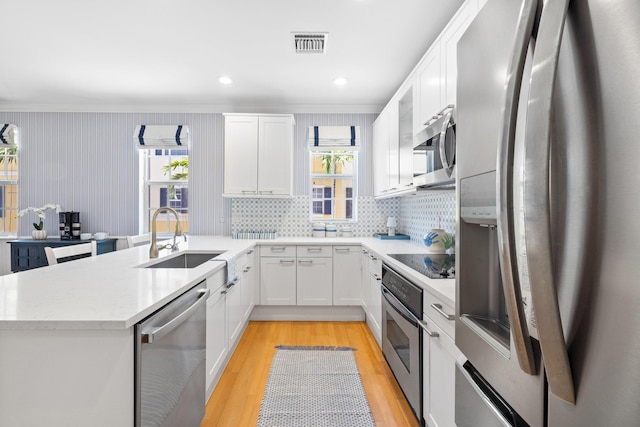 326 Tuxedo Ln, West Palm Beach, FL 33401 - kitchen featuring stainless steel appliances, a peninsula, white cabinetry, plenty of natural light, and ornamental molding