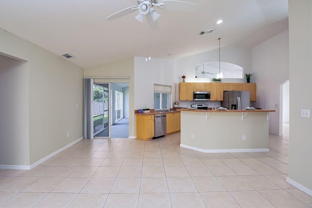 2062 SW Scorpio Ln, Port Saint Lucie, FL 34984 - kitchen with stainless steel appliances, high vaulted ceiling, a ceiling fan, light tile patterned floors, and a kitchen bar