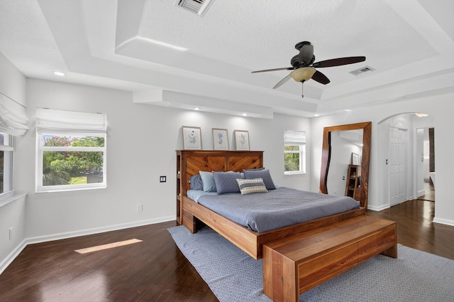 4315 Caryota Dr, Boynton Beach, FL 33436 - bedroom with a tray ceiling, wood finished floors, arched walkways, a ceiling fan, and ensuite bath
