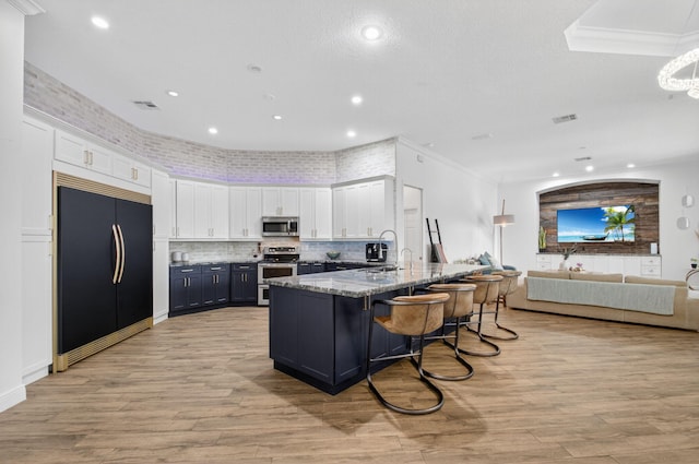 4315 Caryota Dr, Boynton Beach, FL 33436 - kitchen with appliances with stainless steel finishes, white cabinets, light stone countertops, open floor plan, and a kitchen bar
