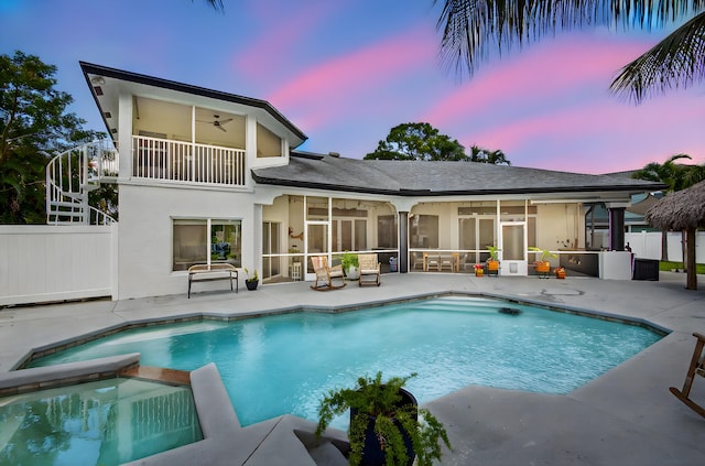 4315 Caryota Dr, Boynton Beach, FL 33436 - back of house at dusk with a ceiling fan, a patio, a balcony, a sunroom, and a pool with connected hot tub
