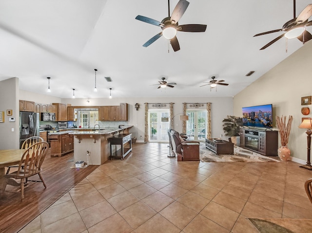 5301 Bald Cypress Trl, Fort Pierce, FL 34951 - kitchen featuring lofted ceiling, open floor plan, stainless steel fridge with ice dispenser, a peninsula, and brown cabinetry