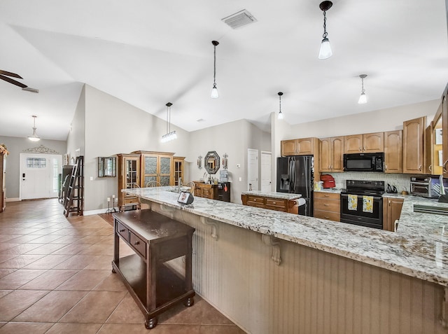 5301 Bald Cypress Trl, Fort Pierce, FL 34951 - kitchen with black appliances, tasteful backsplash, light stone counters, light tile patterned floors, and vaulted ceiling
