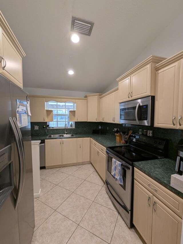 3074 SE Dalhart Rd, Port Saint Lucie, FL 34952 - kitchen featuring stainless steel appliances, cream cabinets, backsplash, vaulted ceiling, and dark countertops