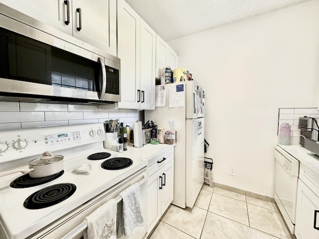 751 Cypress Ln Unit K, Deerfield Beach, FL 33064 - kitchen with white appliances, light tile patterned floors, white cabinetry, backsplash, and a textured ceiling