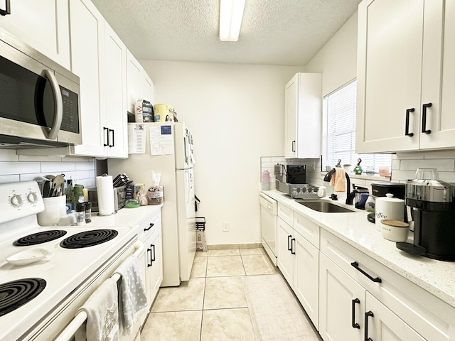 751 Cypress Ln Unit K, Deerfield Beach, FL 33064 - kitchen featuring white appliances, decorative backsplash, white cabinets, a textured ceiling, and light tile patterned floors