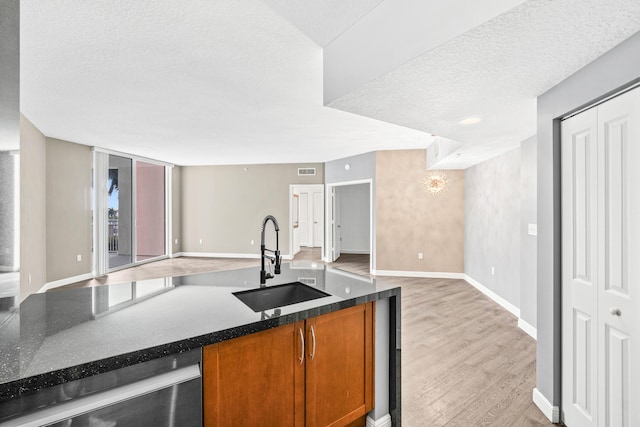 350 N Federal Hwy Unit 609, Boynton Beach, FL 33435 - kitchen featuring open floor plan, brown cabinetry, dishwasher, light wood-style floors, and a textured ceiling
