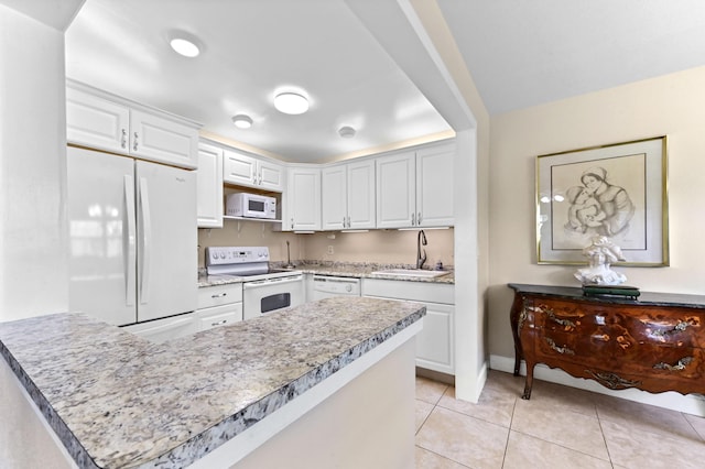 154 Tuscany C, Delray Beach, FL 33446 - kitchen featuring white appliances, white cabinets, light tile patterned floors, a peninsula, and light stone countertops