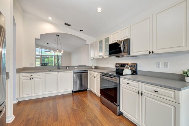 7937 Sonora St, Boynton Beach, FL 33437 - kitchen featuring appliances with stainless steel finishes, wood finished floors, white cabinetry, glass insert cabinets, and arched walkways