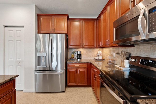 709 SW Sun Cir, Palm City, FL 34990 - kitchen featuring stainless steel appliances, stone counters, tasteful backsplash, light tile patterned floors, and brown cabinetry