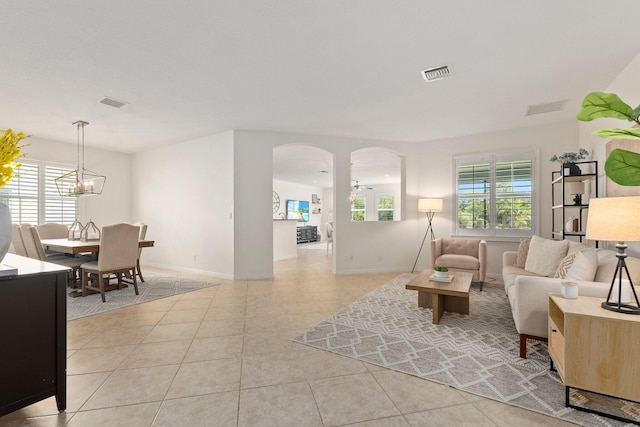 709 SW Sun Cir, Palm City, FL 34990 - living room featuring healthy amount of natural light, light tile patterned floors, arched walkways, and a chandelier