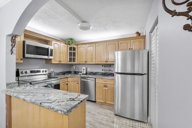 512 Shady Pine Way Unit B1, Greenacres, FL 33415 - kitchen featuring appliances with stainless steel finishes, glass insert cabinets, light stone countertops, a textured ceiling, and a peninsula