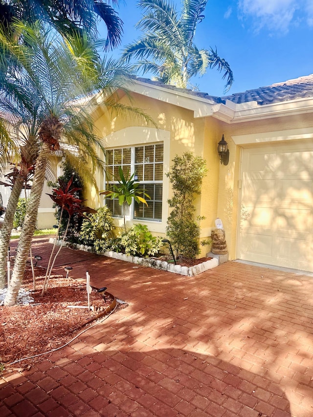 5200 Rising Comet Ln, Greenacres, FL 33463 - view of exterior entry with stucco siding, decorative driveway, and a garage