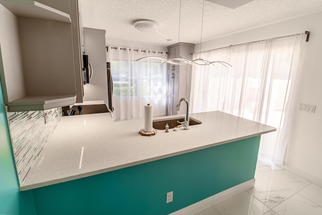 8129 Sedgewick Ct Unit 29-A, Lake Clarke Shores, FL 33406 - kitchen featuring plenty of natural light, a peninsula, light marble finish floors, a textured ceiling, and pendant lighting