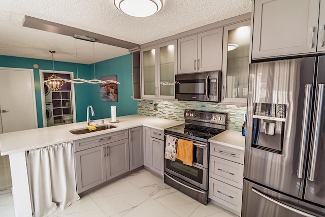 8129 Sedgewick Ct Unit 29-A, Lake Clarke Shores, FL 33406 - kitchen featuring appliances with stainless steel finishes, gray cabinetry, stacked washer and clothes dryer, a peninsula, and a textured ceiling