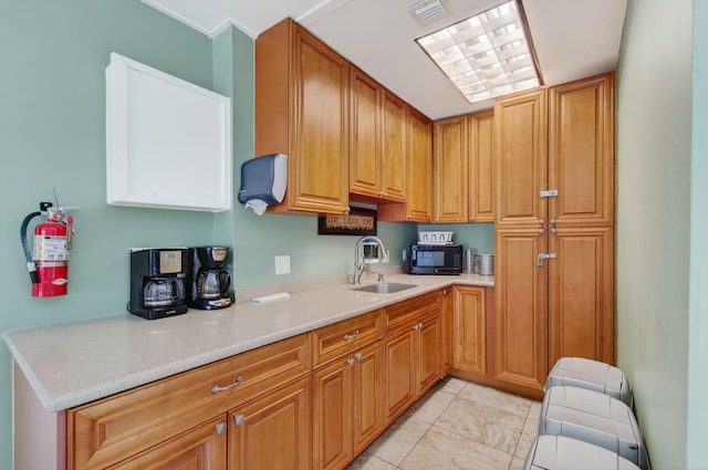 2520 SW Natura Blvd, Deerfield Beach, FL 33441 - kitchen with black microwave, light countertops, light tile patterned floors, and brown cabinets