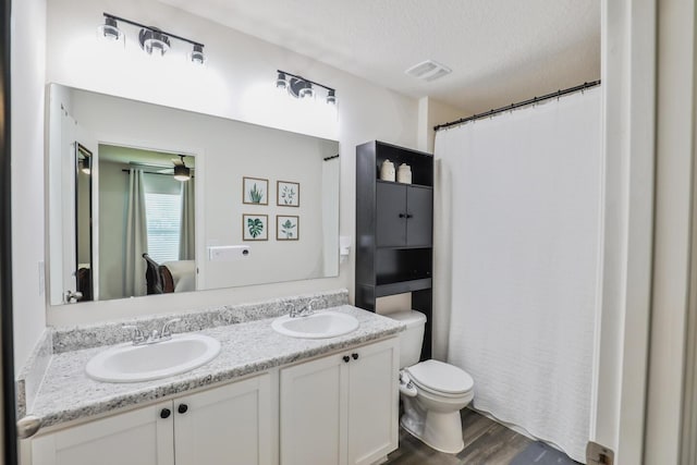 1937 SW Aguero St, Port Saint Lucie, FL 34953 - bathroom featuring double vanity, a textured ceiling, and wood finished floors