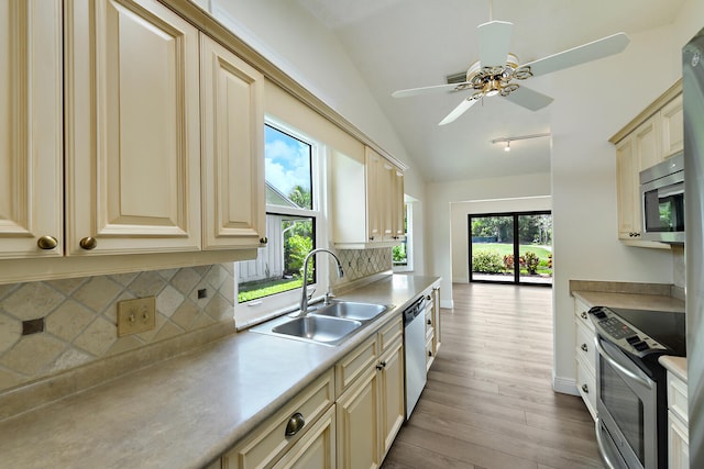 13116 SE Point O Woods Ct, Hobe Sound, FL 33455 - kitchen with stainless steel appliances, cream cabinets, wood finished floors, and vaulted ceiling
