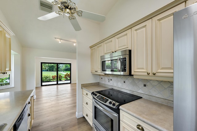 13116 SE Point O Woods Ct, Hobe Sound, FL 33455 - kitchen featuring appliances with stainless steel finishes, cream cabinets, decorative backsplash, light wood-type flooring, and lofted ceiling