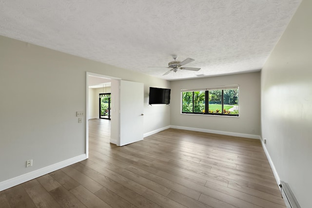13116 SE Point O Woods Ct, Hobe Sound, FL 33455 - unfurnished room with a textured ceiling, a baseboard heating unit, healthy amount of natural light, wood finished floors, and ceiling fan