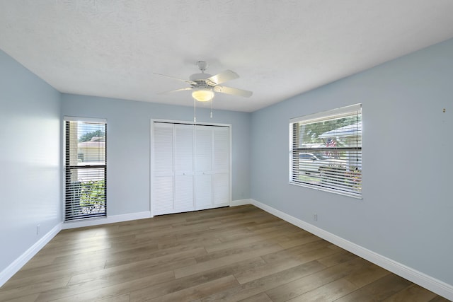 13116 SE Point O Woods Ct, Hobe Sound, FL 33455 - unfurnished bedroom featuring multiple windows, wood finished floors, a closet, and a ceiling fan