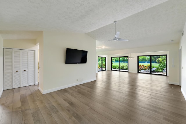 13116 SE Point O Woods Ct, Hobe Sound, FL 33455 - unfurnished living room with a textured ceiling, a ceiling fan, wood finished floors, and lofted ceiling
