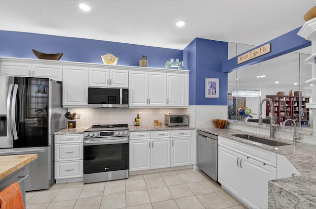 10853 Royal Caribbean Cir, Boynton Beach, FL 33437 - kitchen with stainless steel appliances, tasteful backsplash, white cabinets, light stone counters, and recessed lighting