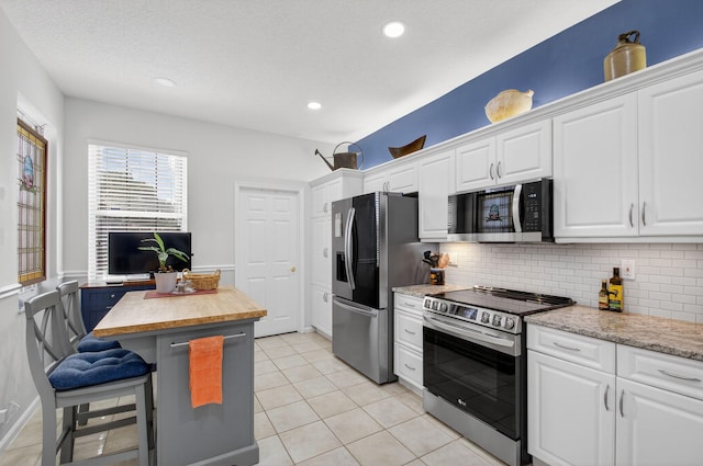10853 Royal Caribbean Cir, Boynton Beach, FL 33437 - kitchen featuring stainless steel appliances, white cabinetry, backsplash, a breakfast bar area, and recessed lighting