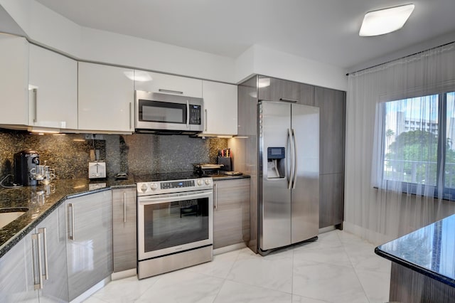 7260 Kinghurst Dr Unit 401, Delray Beach, FL 33446 - kitchen with appliances with stainless steel finishes, modern cabinets, dark stone countertops, and white cabinetry