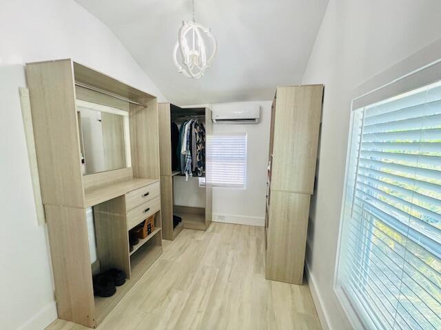 181 NE 15th Ter, Boca Raton, FL 33432 - walk in closet featuring vaulted ceiling, a wall unit AC, light wood-type flooring, and a chandelier