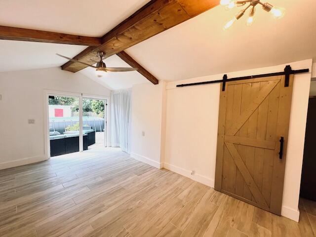 181 NE 15th Ter, Boca Raton, FL 33432 - unfurnished living room with a barn door, light wood finished floors, ceiling fan, and a chandelier