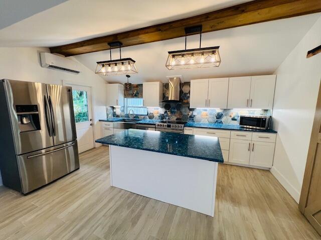 181 NE 15th Ter, Boca Raton, FL 33432 - kitchen with appliances with stainless steel finishes, wall chimney exhaust hood, a wall unit AC, tasteful backsplash, and white cabinetry