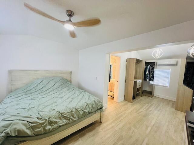 181 NE 15th Ter, Boca Raton, FL 33432 - bedroom with lofted ceiling, an AC wall unit, light wood-type flooring, and a ceiling fan