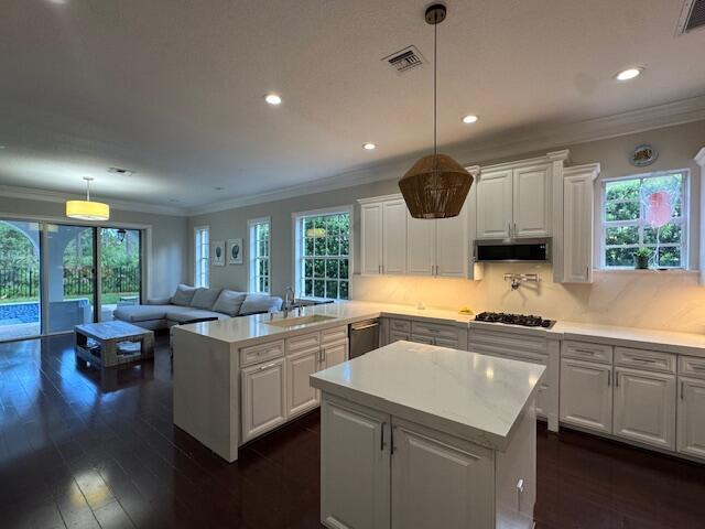 1913 Flower Dr, Palm Beach Gardens, FL 33410 - kitchen with gas stovetop, a center island, light countertops, ornamental molding, and stainless steel dishwasher